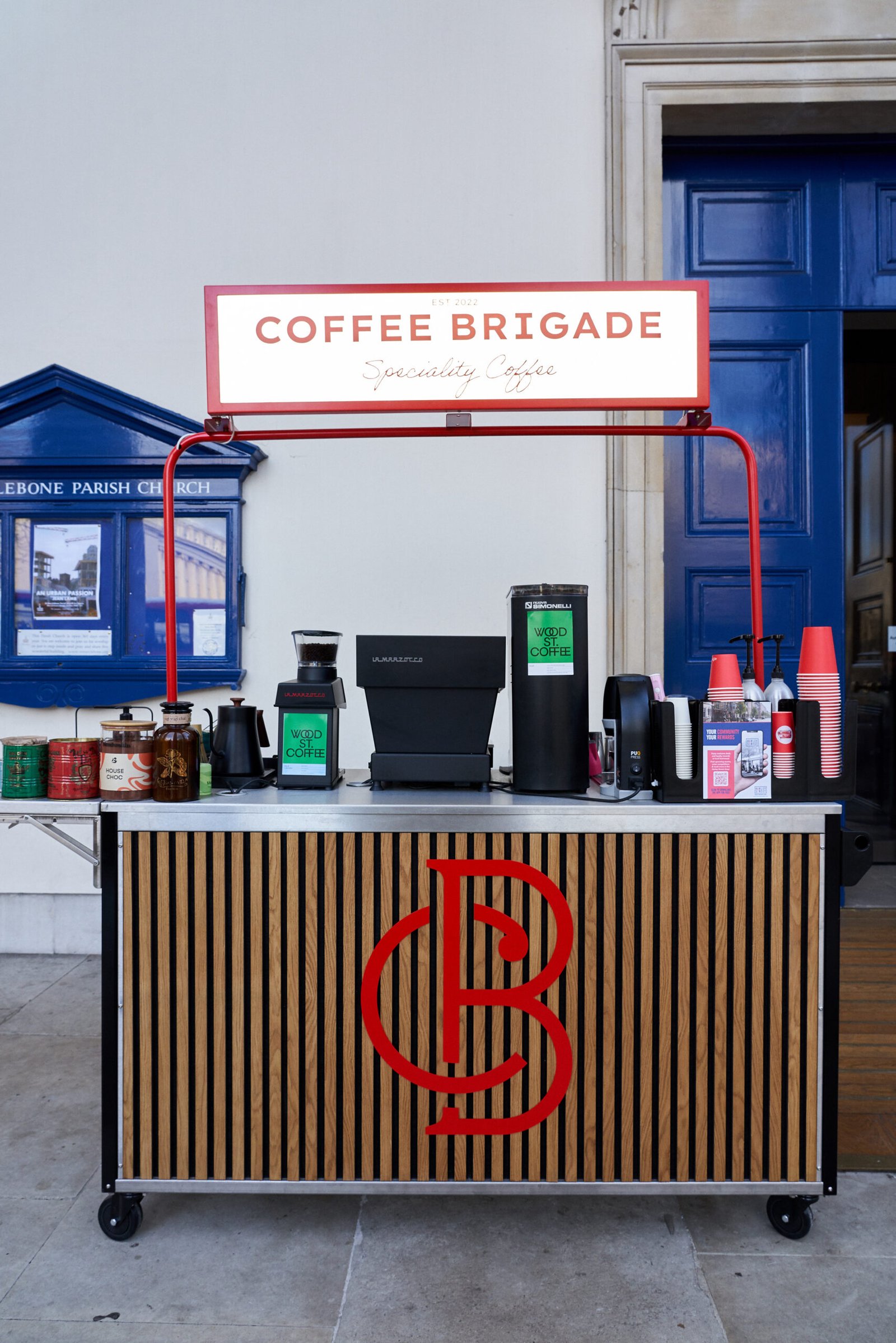 The Coffee Brigade cart outside St Marylebone Parish Church, with its red sign and wood-slat front